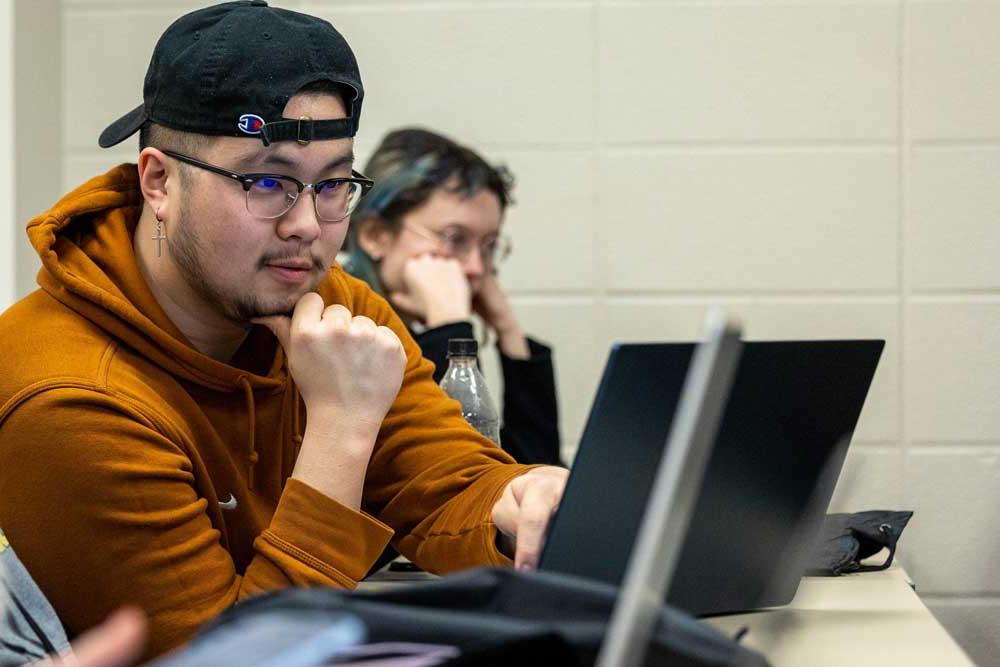 young male college student studying on laptop